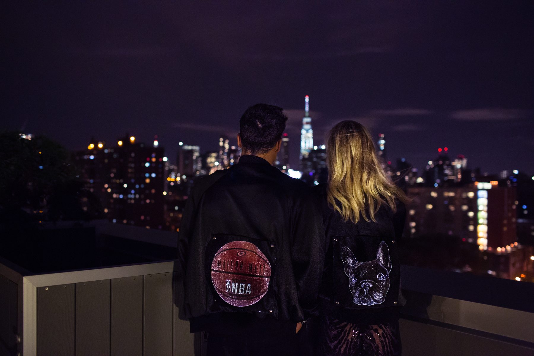 Illuminated bomber jacket patches on a rooftop at night